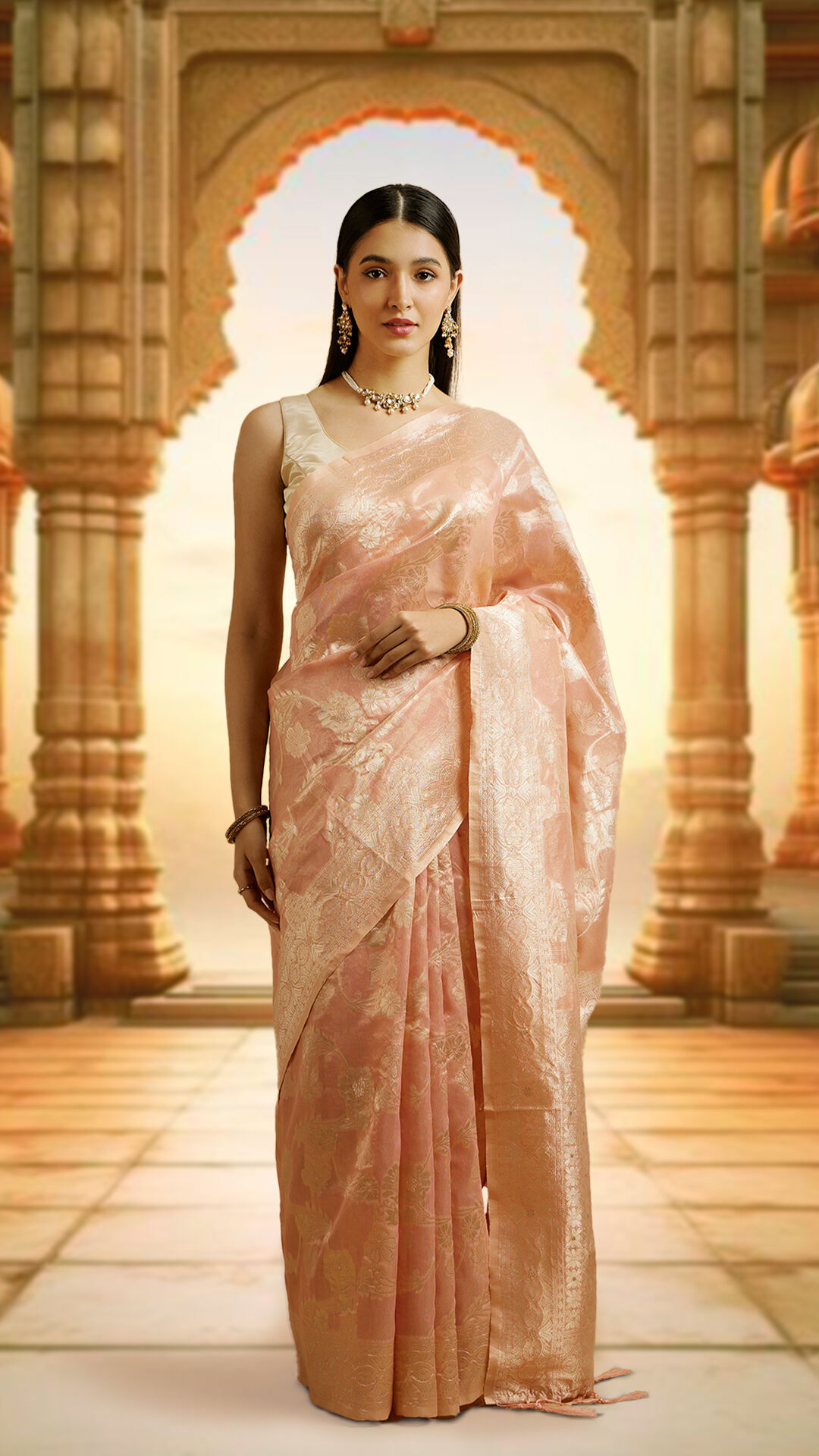 Sophisticated woman adorned in an elegant pink silk zari saree, complemented by exquisite earrings and a necklace.